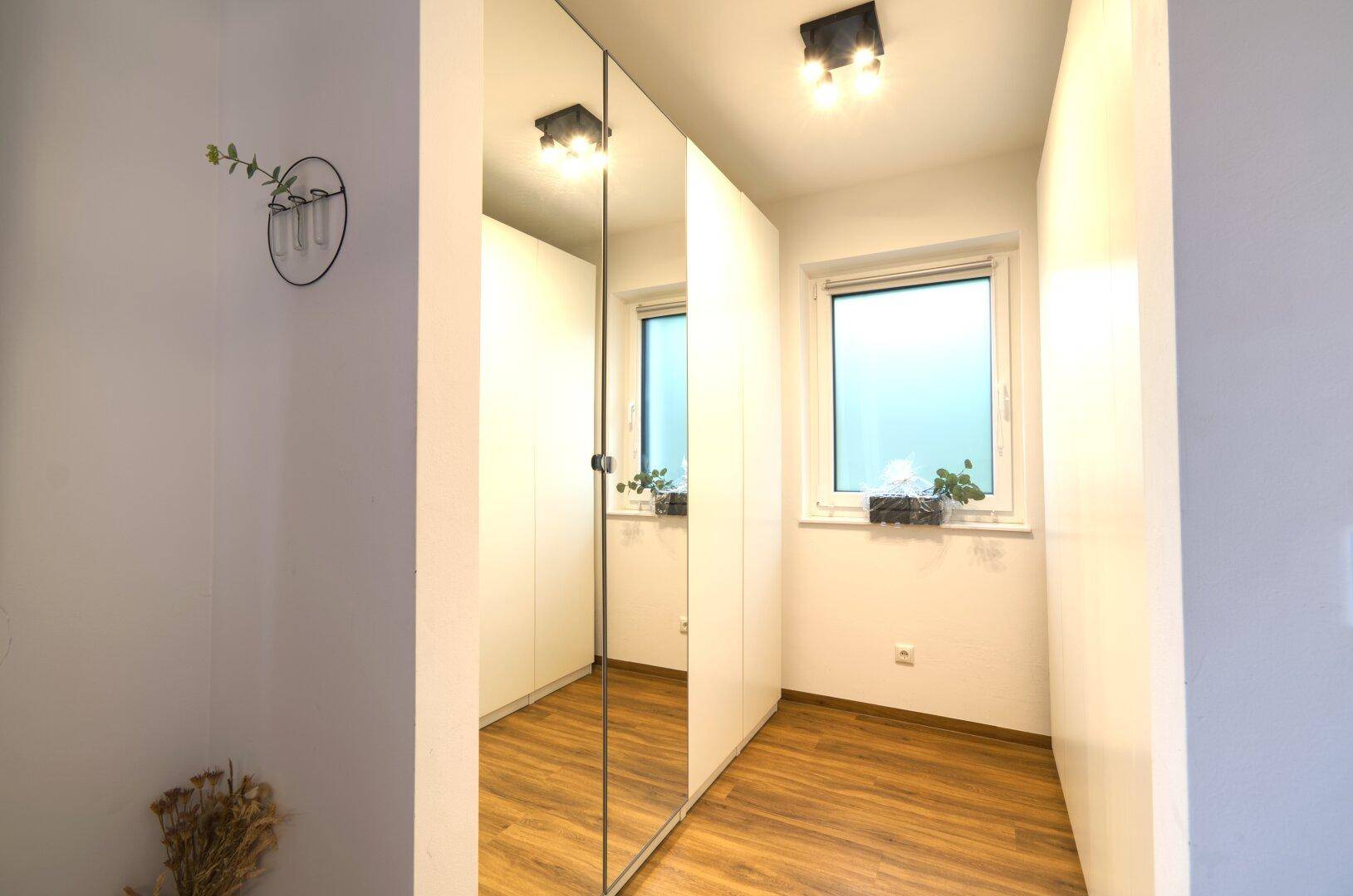 Kleiner Raum mit Spiegelschränken und Fenster, ideal als Ankleidebereich.