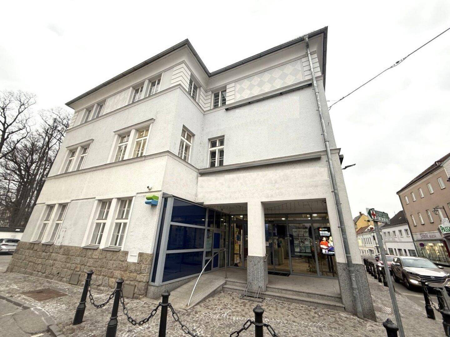 Ansicht des Gebäudes von der Seite mit modernisiertem Eingangsbereich und großen Fenstern.