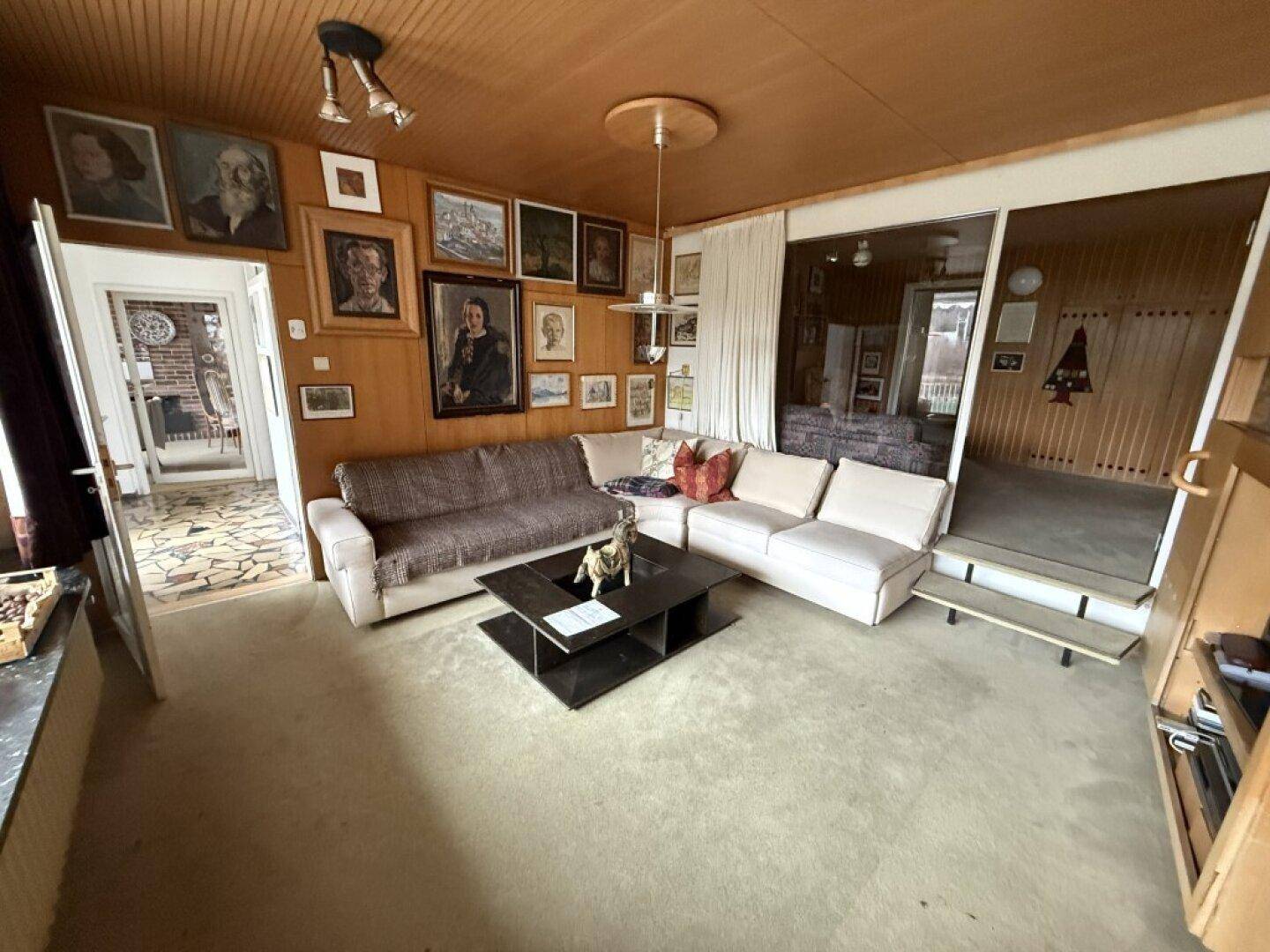 Geräumiges Wohnzimmer mit bequemen Sofas, Holzbalkendecke und einer Sammlung von Kunstwerken.