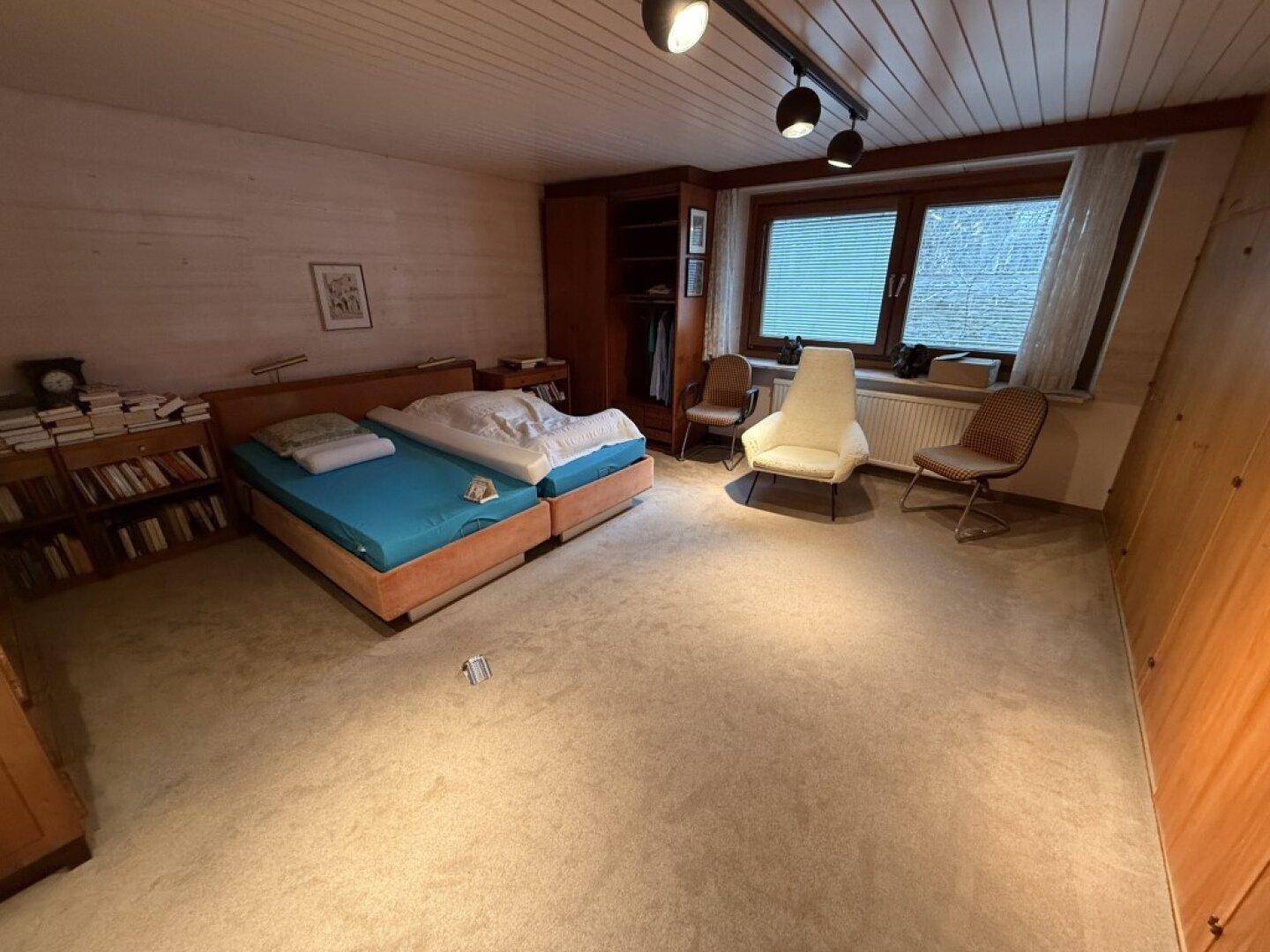 Schlafzimmer mit zwei Einzelbetten, Teppichboden und Holzvertäfelung an der Decke.