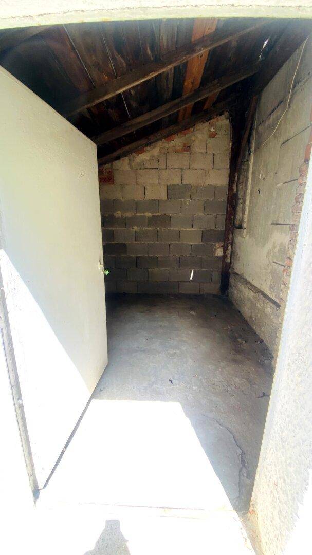 Kleiner Abstellraum mit unverputzten Wänden, sichtbarer Dachkonstruktion und Betonboden.