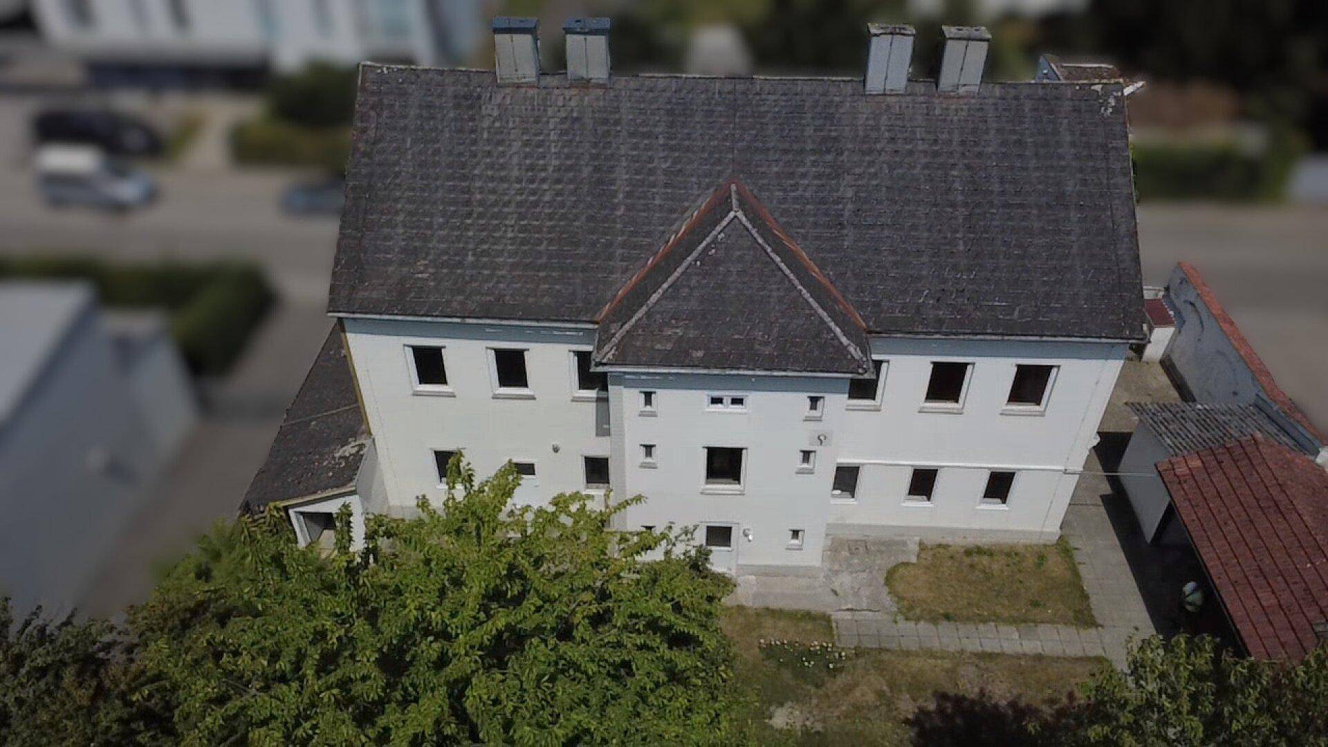 Luftaufnahme des Gebäudes mit Satteldach und umliegendem Grundstück, umgeben von Bäumen.