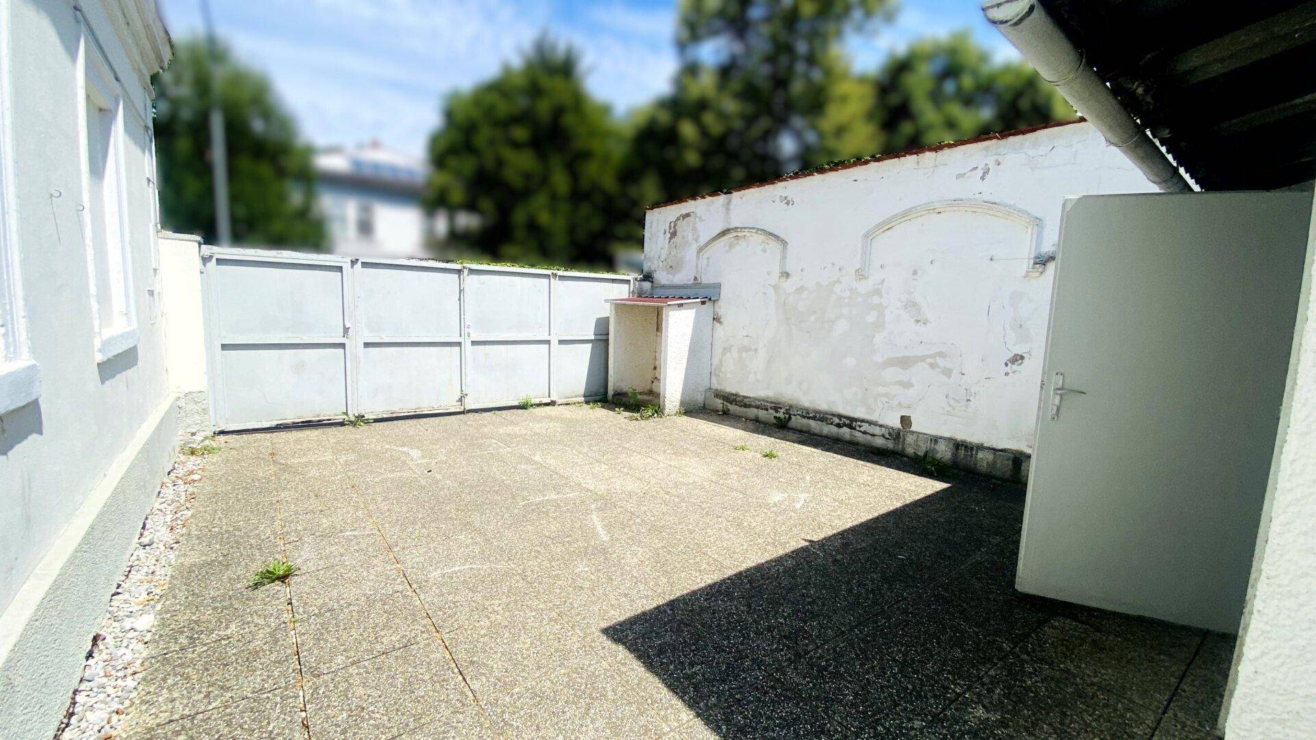 Gepflasterter Innenhof mit hohen Mauern und einer Tür, ideal für einen Sitzbereich im Freien.