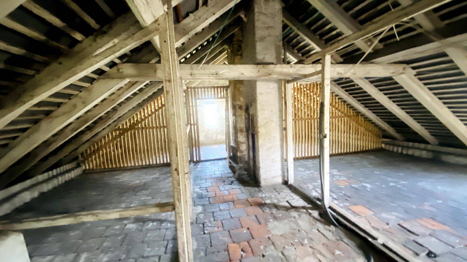 Geräumiger Dachboden mit sichtbarer Holzkonstruktion und Ziegelboden, bereit zum Ausbau.
