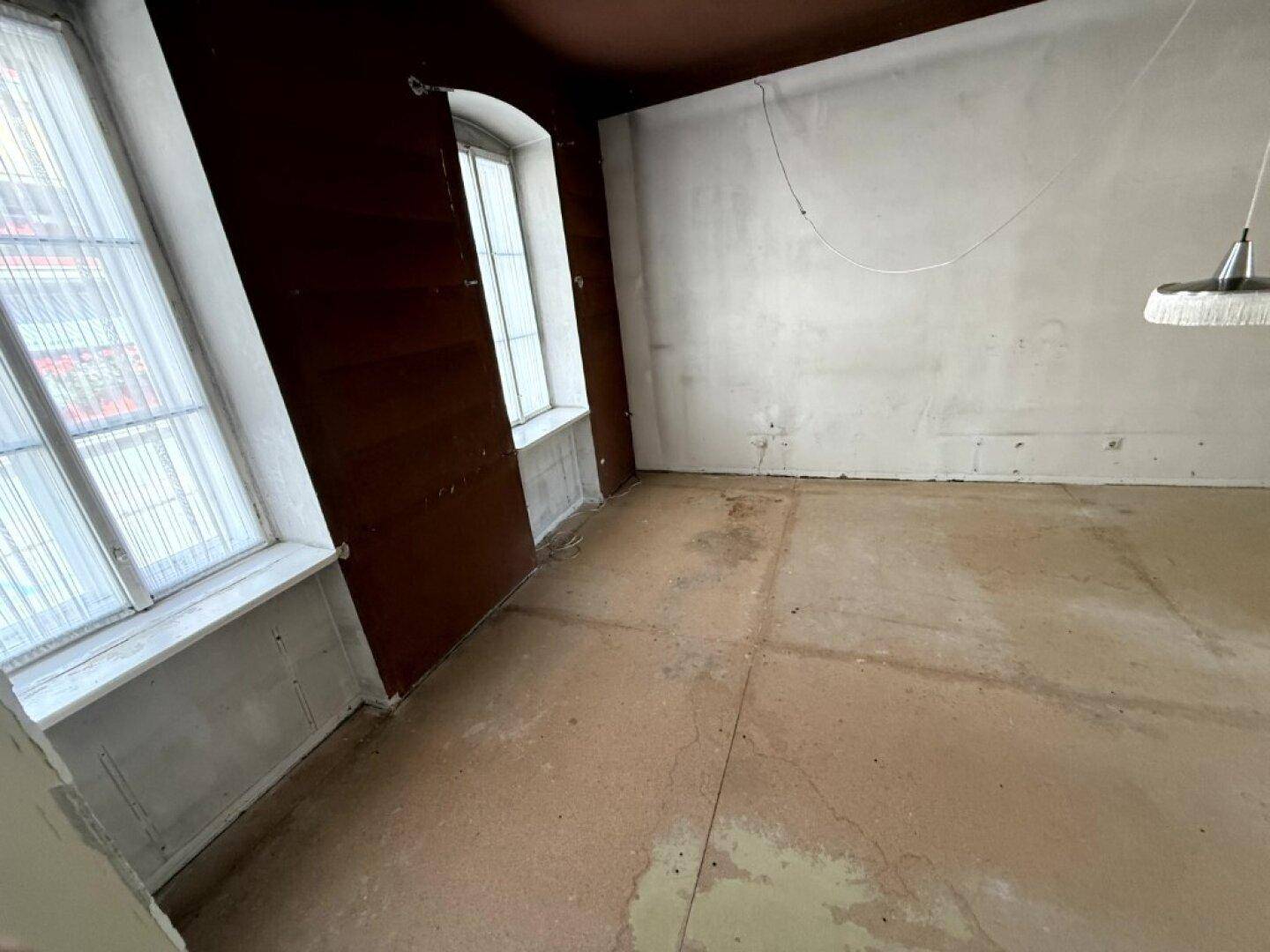 Leerer Raum mit kahlen Wänden und dunkler Decke, der auf Renovierungsbedarf hindeutet.