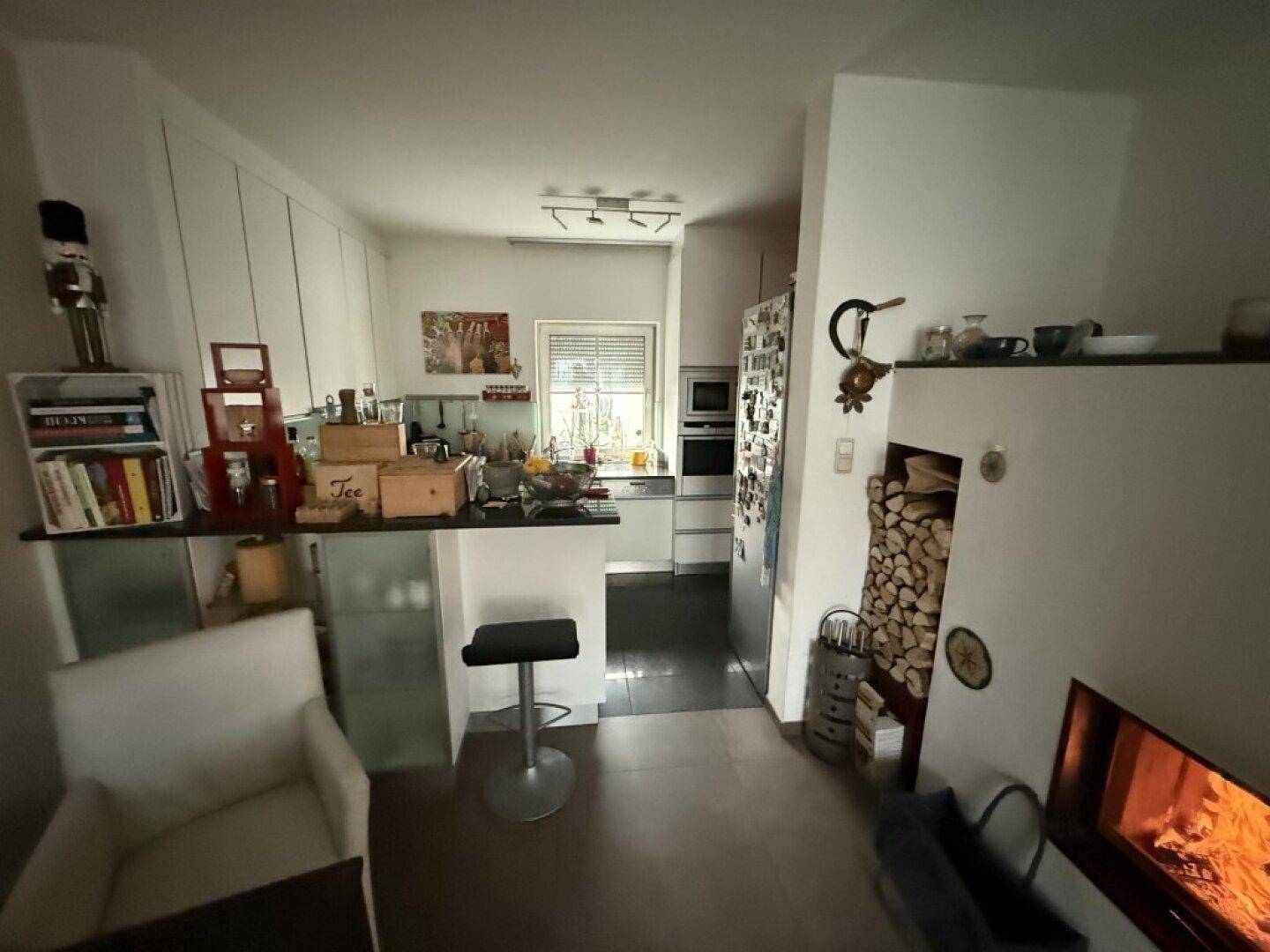 Funktionale Küche mit Frühstücksbar, weißen Schränken und Blick auf den Kaminbereich.