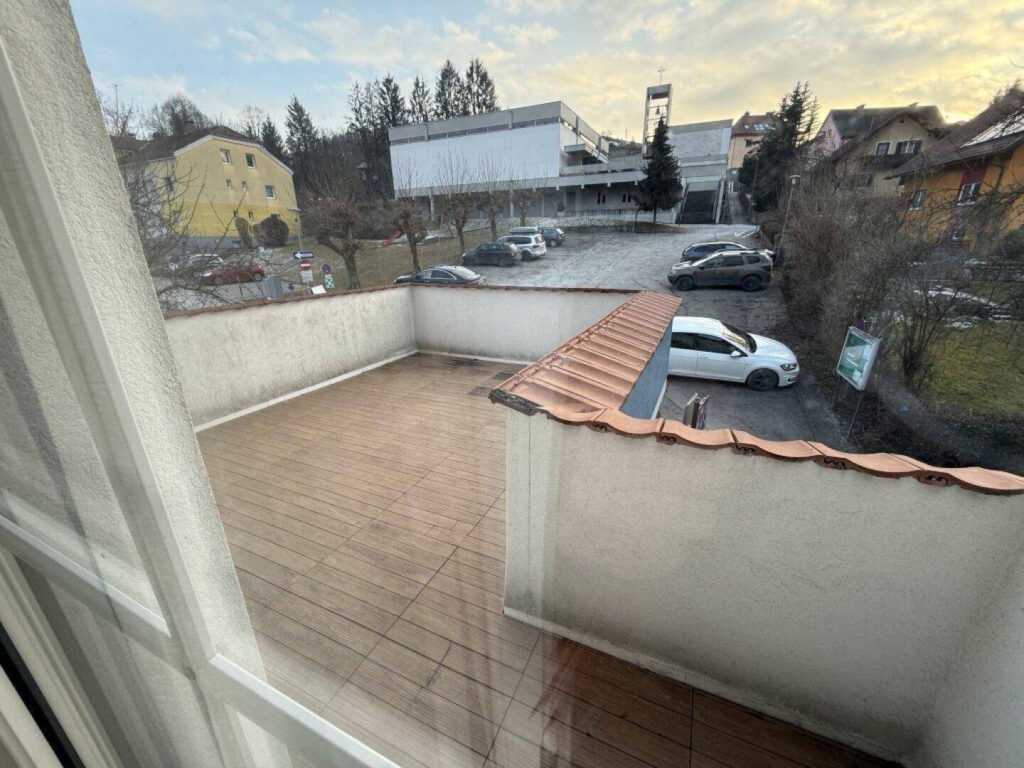 Geräumige Terrasse mit Fliesenboden und niedrigen Mauern, umgeben von der Nachbarschaft.