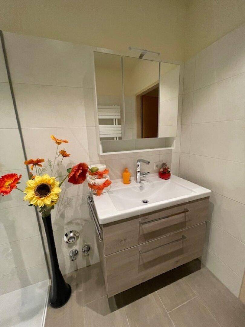 Heller Waschtisch mit Spiegelschrank und beheiztem Handtuchhalter im Badezimmer.