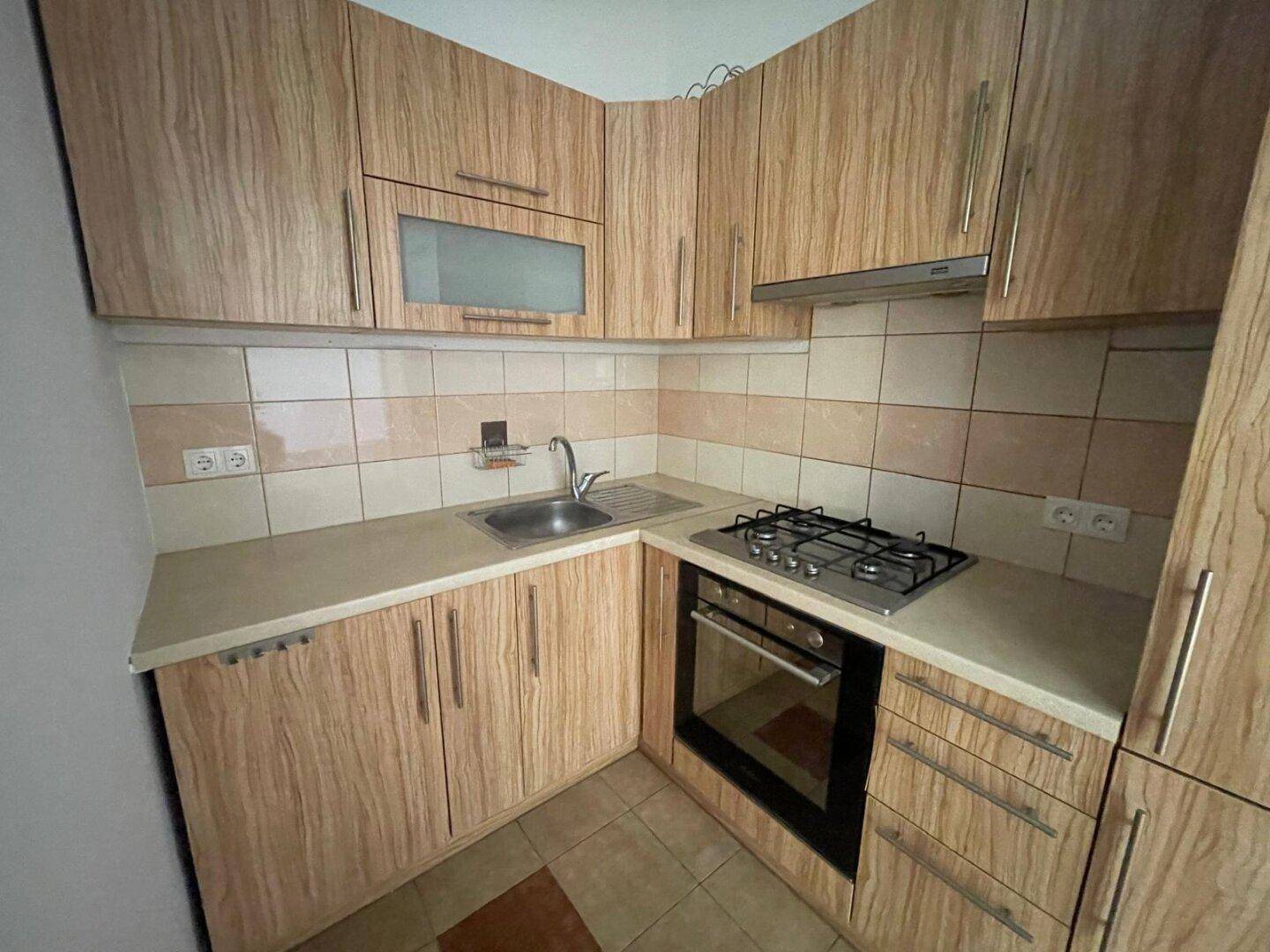 Funktionale Küche mit Holzschränken, Gasherd und integriertem Backofen, ideal für den täglichen Gebrauch.