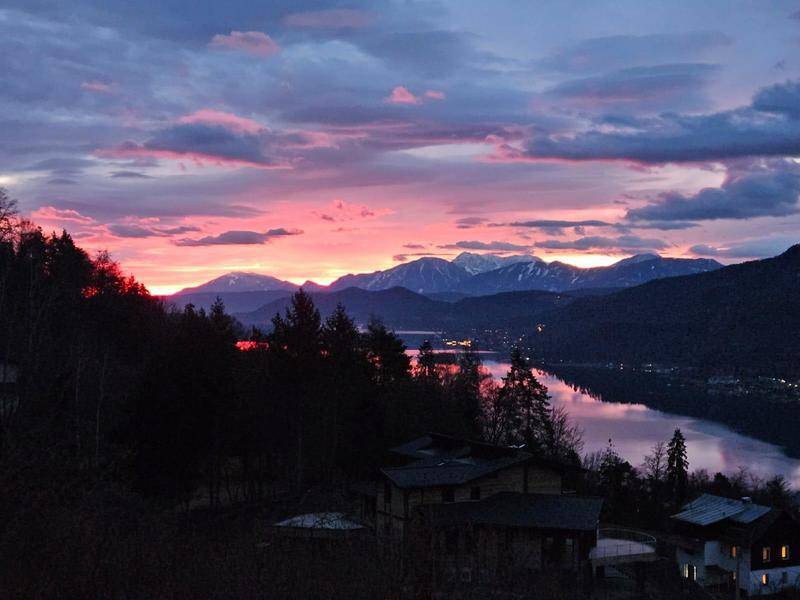 Spektakulärer Sonnenuntergang über dem See mit leuchtenden Farben am Himmel und Bergkulisse.
