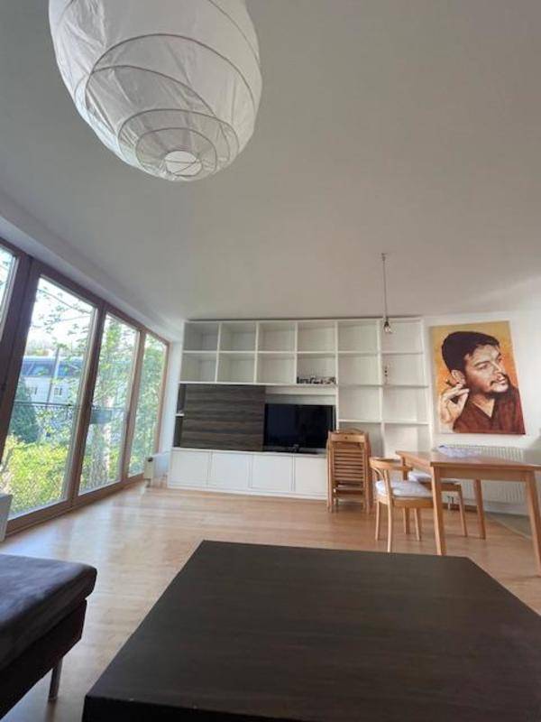 Helles Wohn- und Esszimmer mit großen Fenstern, Holzboden und Blick ins Grüne.