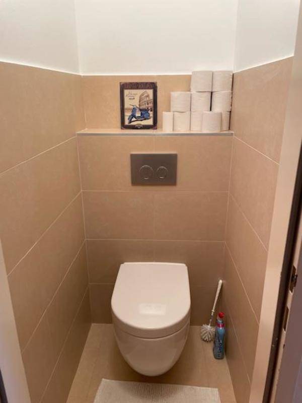 Kleines Gäste-WC mit wandhängender Toilette und beigefarbenen Fliesen.