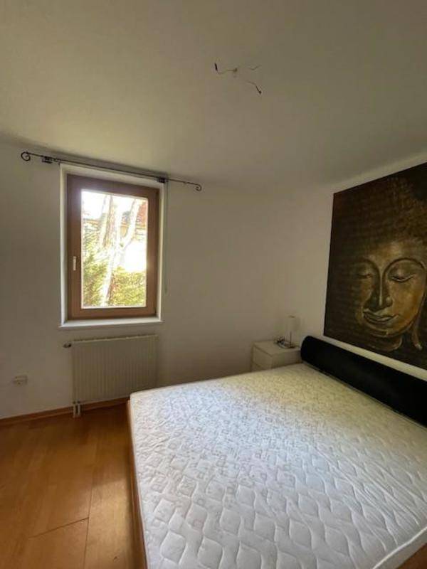 Helles Schlafzimmer mit Holzboden, Fenster und Blick ins Grüne.