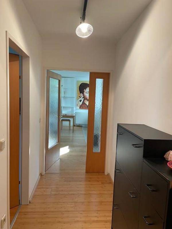 Heller Flur mit Holzboden und einem Blick in den angrenzenden Wohnbereich.