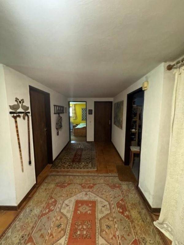 Langer Flur mit Teppichen, Holzböden und mehreren Türen zu angrenzenden Räumen im Haus.