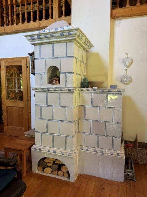Traditioneller Kachelofen mit Holzscheiten und kunstvollen Verzierungen in einem gemütlichen Wohnbereich.