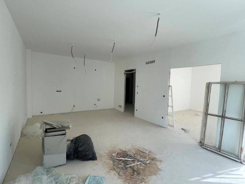 Unfertiger Innenraum mit weißen Wänden, Betonboden und sichtbaren Elektroinstallationen, bereit für den Ausbau.