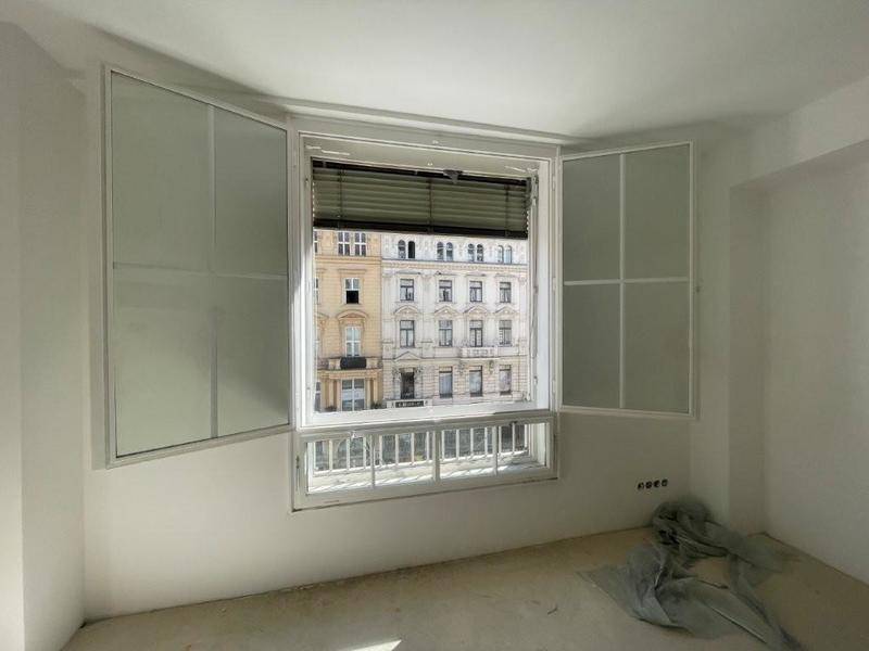Heller Raum im Rohbau mit großem Fenster, Blick auf die Stadt und vorbereiteten Wänden.