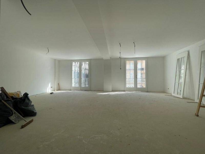 Großer Raum im Rohbau mit zwei französischen Balkontüren, viel Tageslicht und vorbereiteten Wänden.