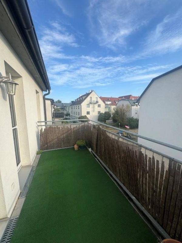 Langer Balkon mit Kunstrasen und Sichtschutz, Blick auf die Nachbarschaft.