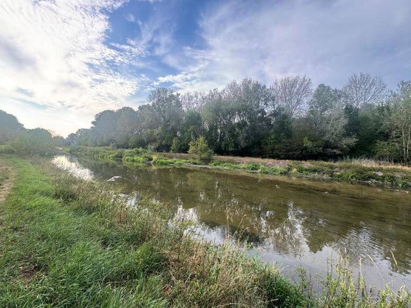 Ruhiger Fluss oder Kanal umgeben von üppiger Vegetation und Bäumen.