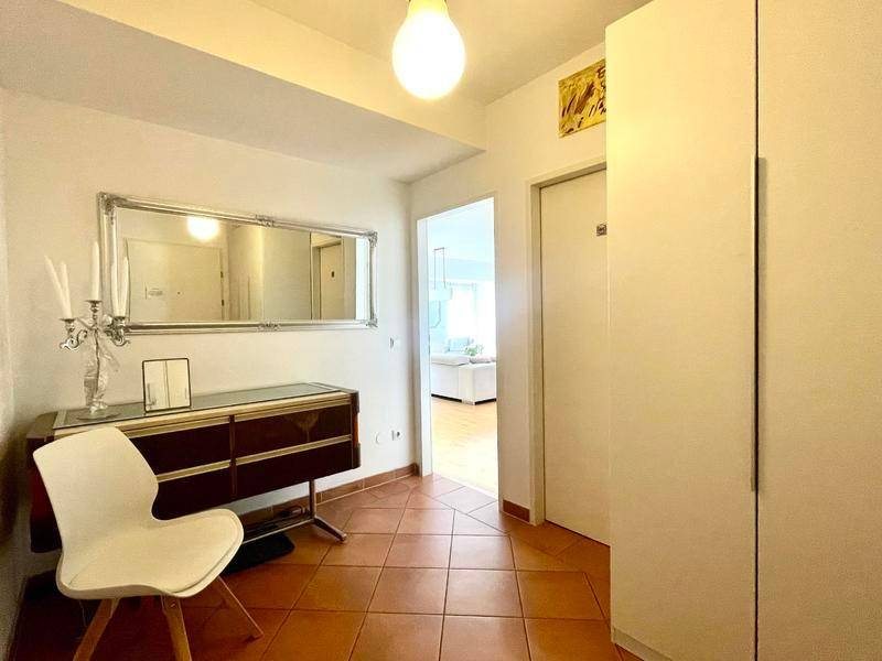 Heller Flur mit Terrakottafliesen, großem Spiegel und weißem Einbauschrank.