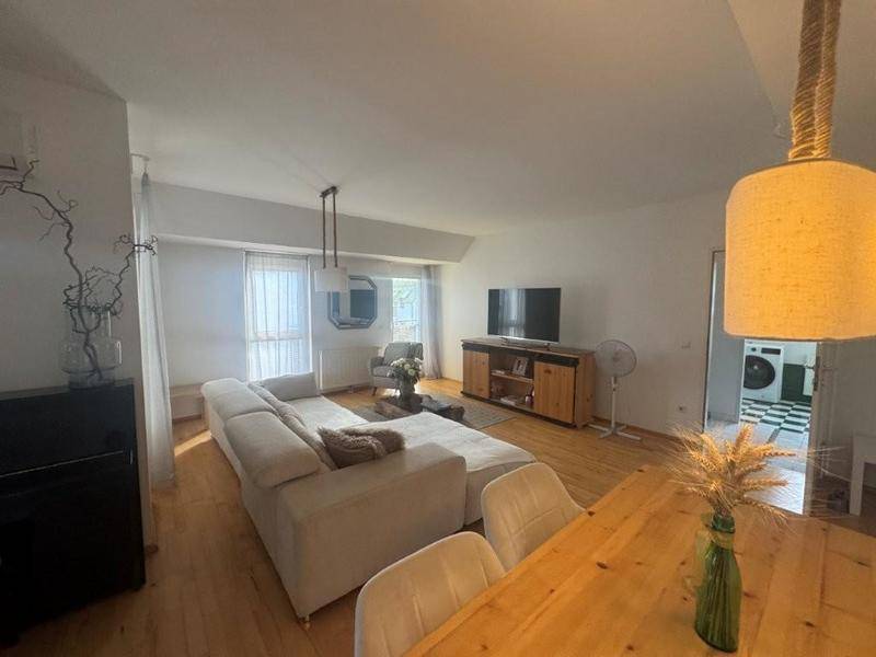 Offener Wohn- und Essbereich mit hellem Sofa, Esstisch und Fernseher.
