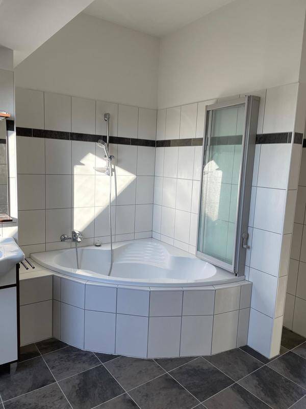 Badezimmer mit Eckbadewanne, Duschabtrennung und modernen Fliesen.