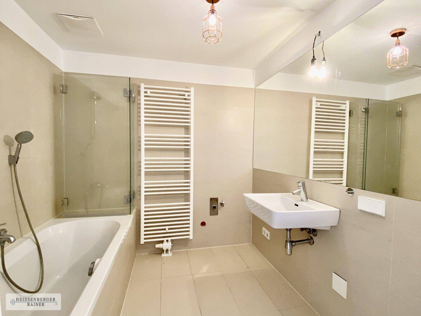 Modernes Badezimmer mit Badewanne, Dusche, Waschbecken und beheiztem Handtuchhalter.