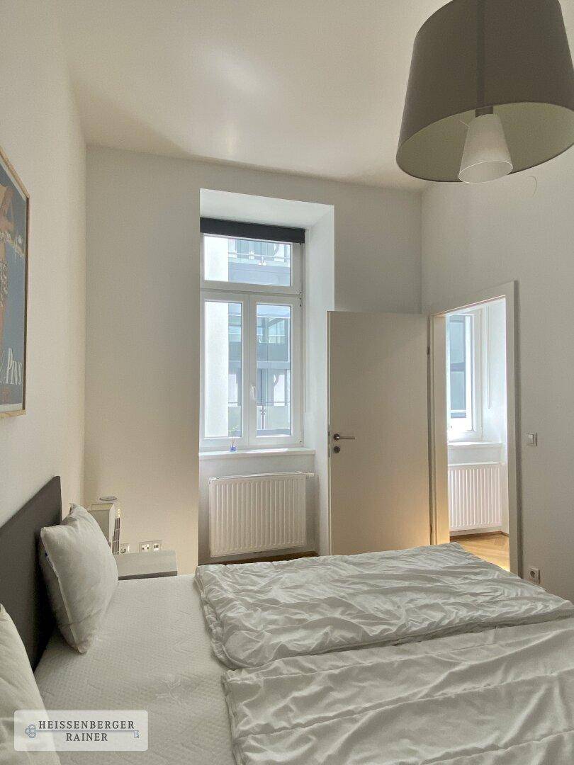 Schlafzimmer mit Parkettboden und Fenster, das viel Tageslicht hereinlässt, für eine helle Atmosphäre.