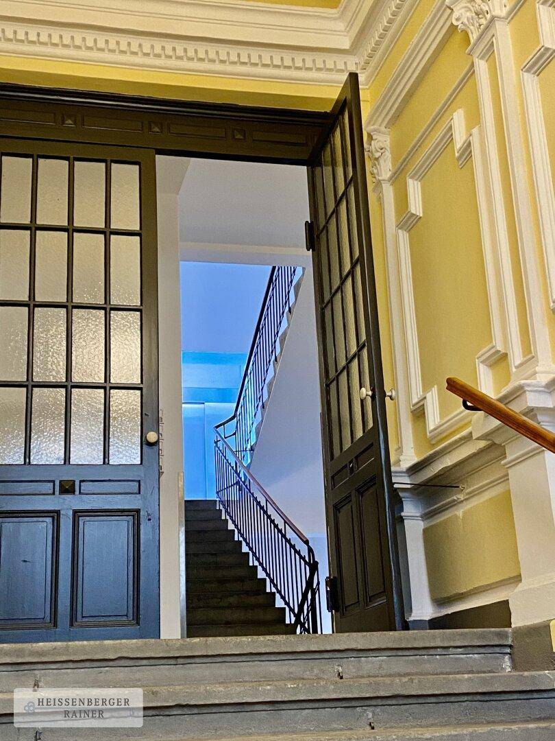 Elegantes Treppenhaus mit verzierten Türen, Stuckelementen und geschwungener Treppe.