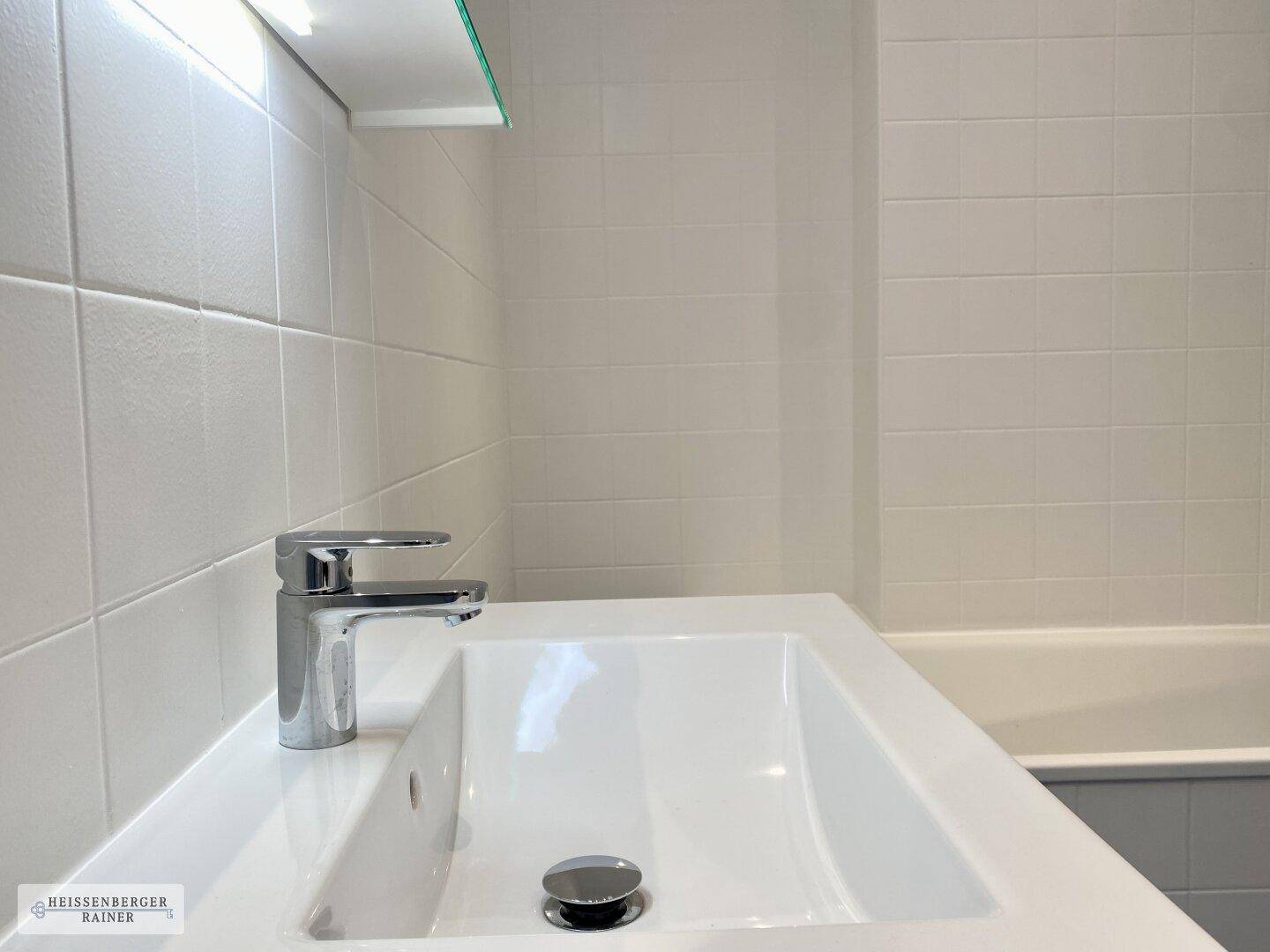 Modernes Waschbecken mit Armatur und weißen Fliesen im Badezimmer.