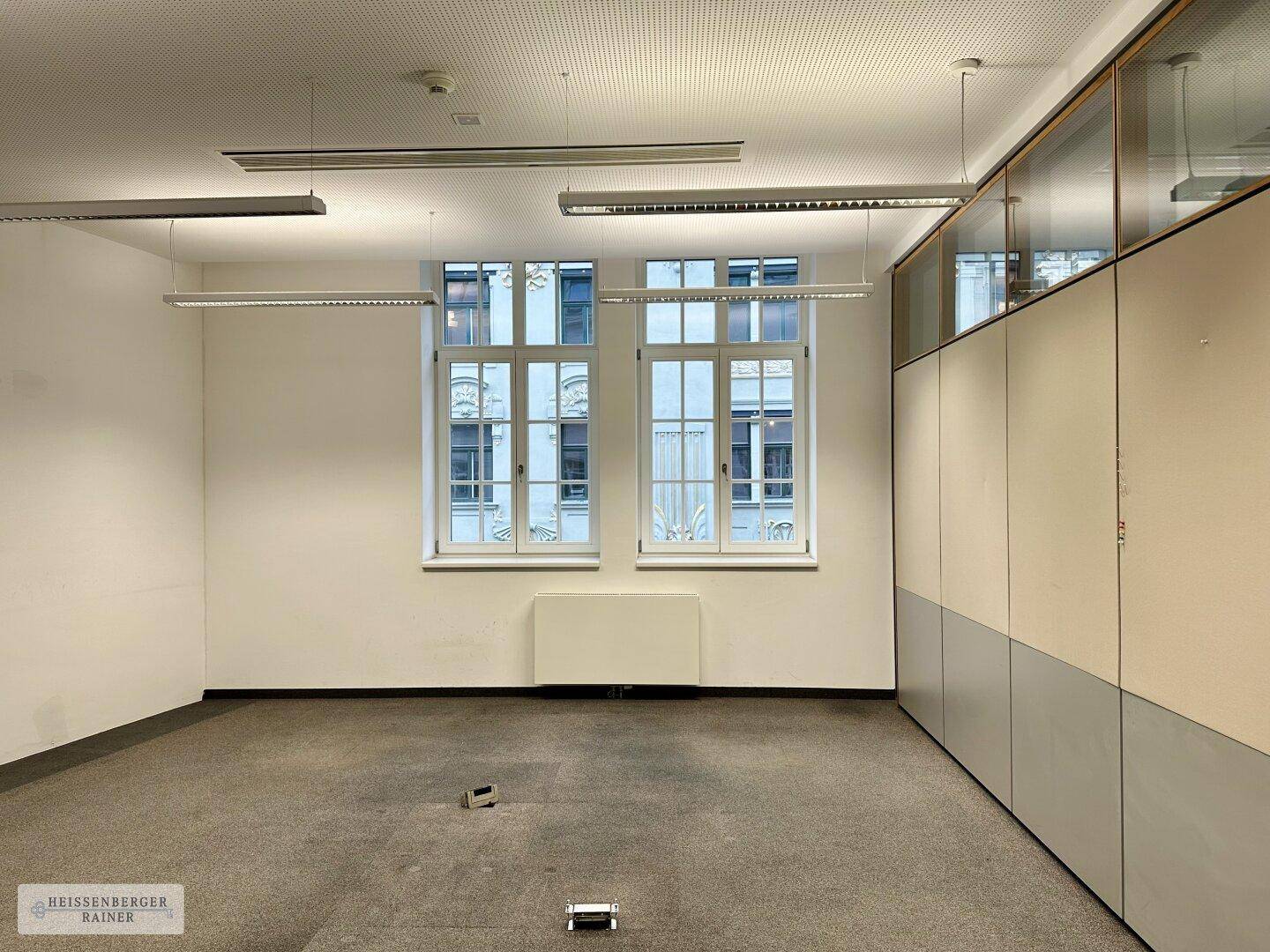 Helles Büro mit Teppichboden, großen Fenstern und praktischen Einbauschränken.