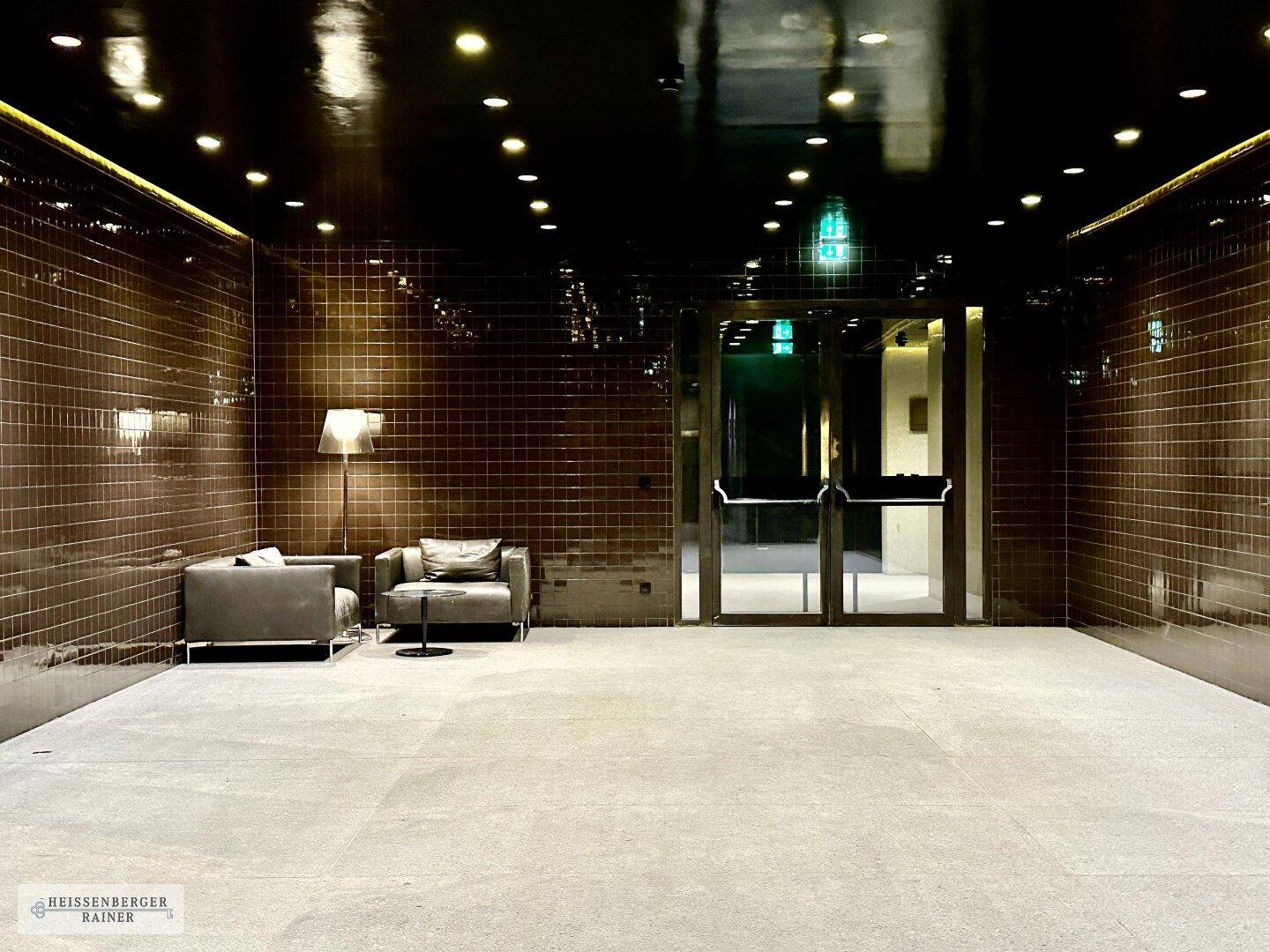 Elegante Lobby mit dunklen Fliesenwänden, eingelassenen Lichtern und bequemen Sitzgelegenheiten.
