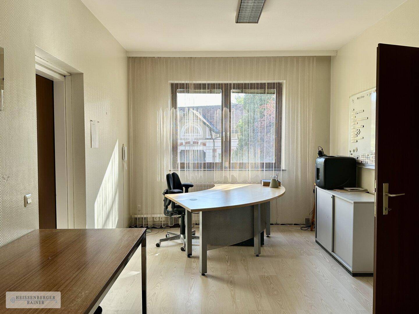 Helles Einzelbüro mit geschwungenem Schreibtisch, Fenster und Blick auf die Umgebung.