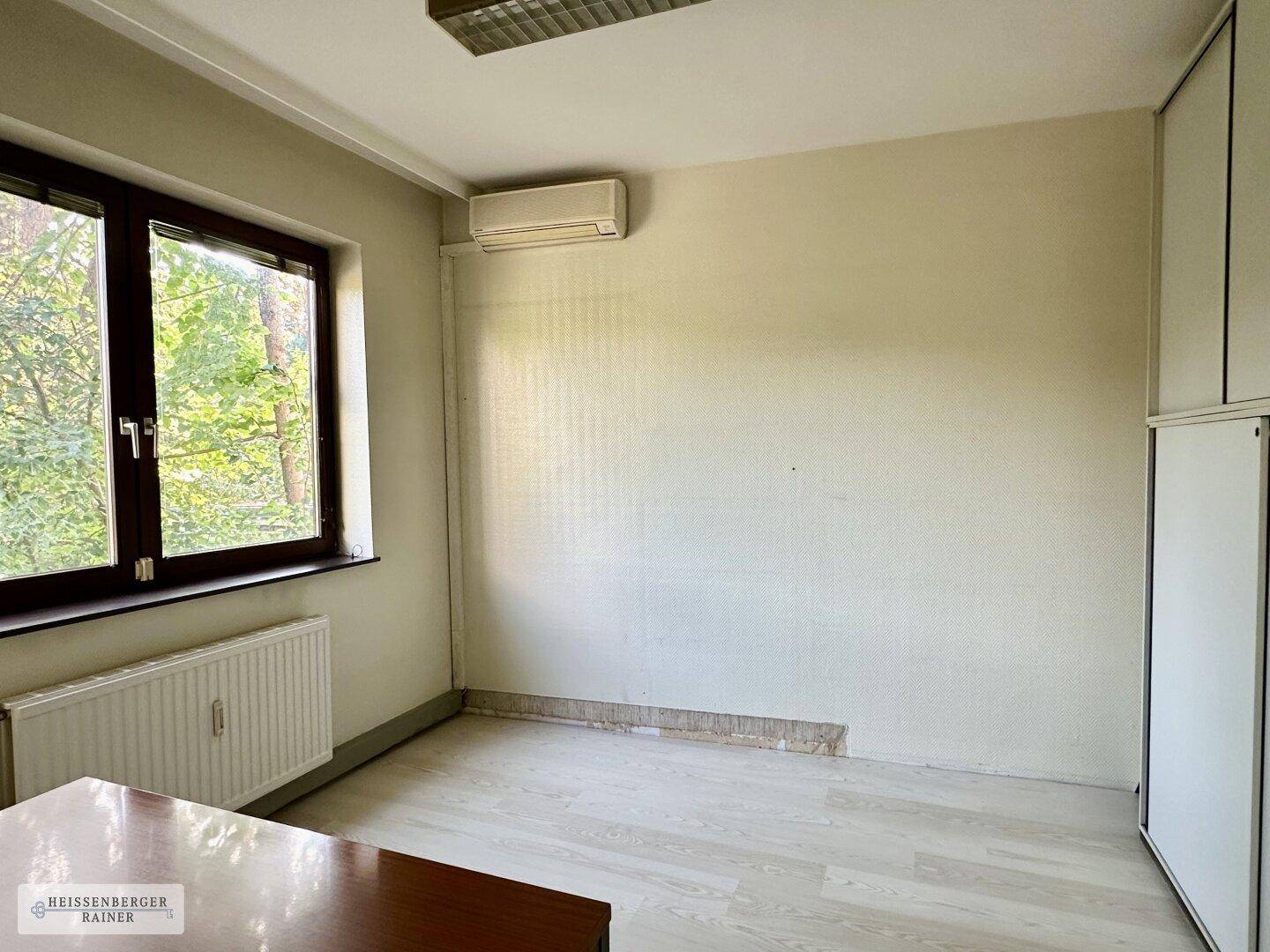 Büro mit Klimaanlage, Fenster und Blick ins Grüne, bereit zur Einrichtung.