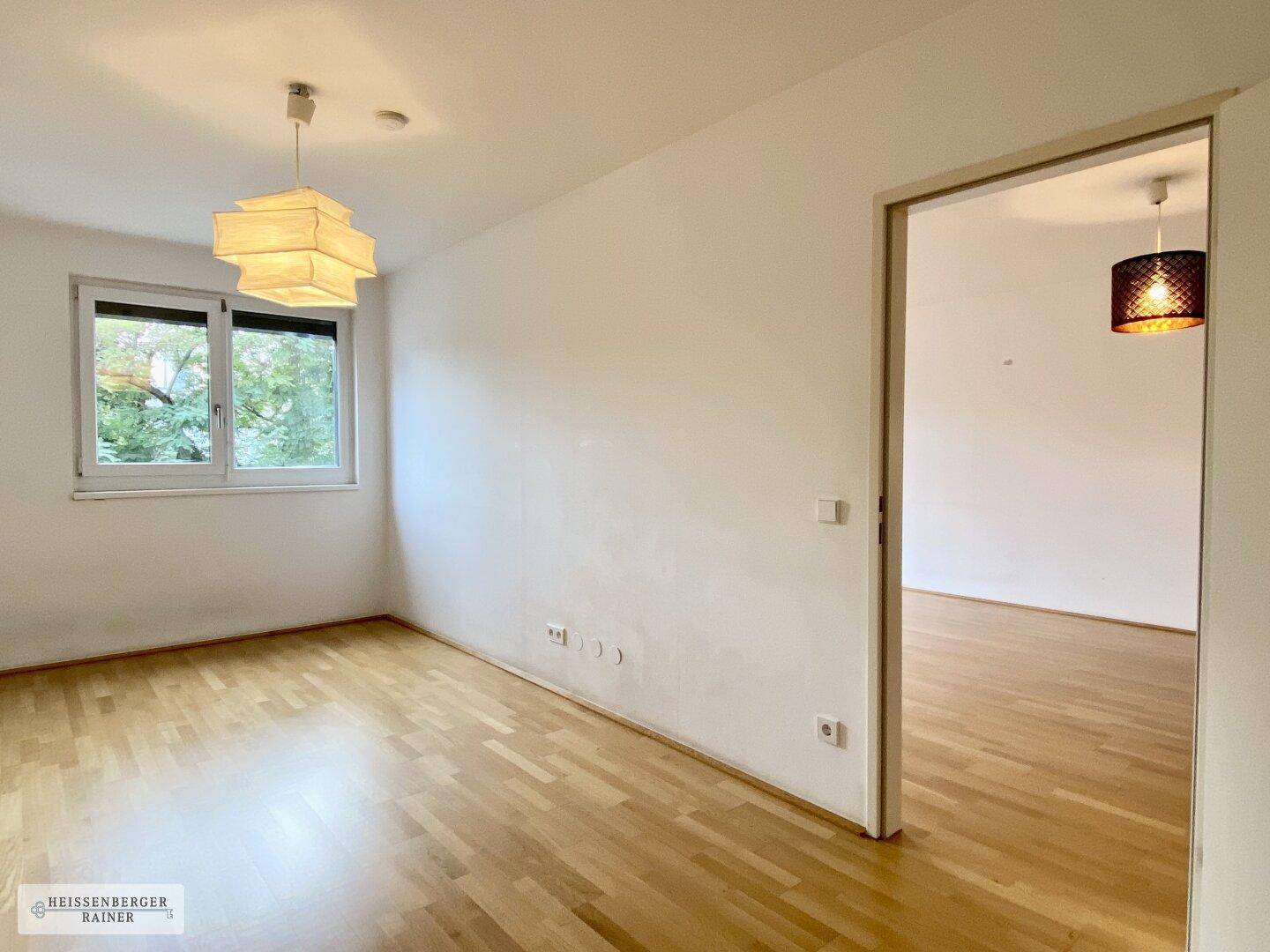 Helles, leeres Zimmer mit Holzboden und Fenster, ideal als Schlafzimmer oder Büro nutzbar.
