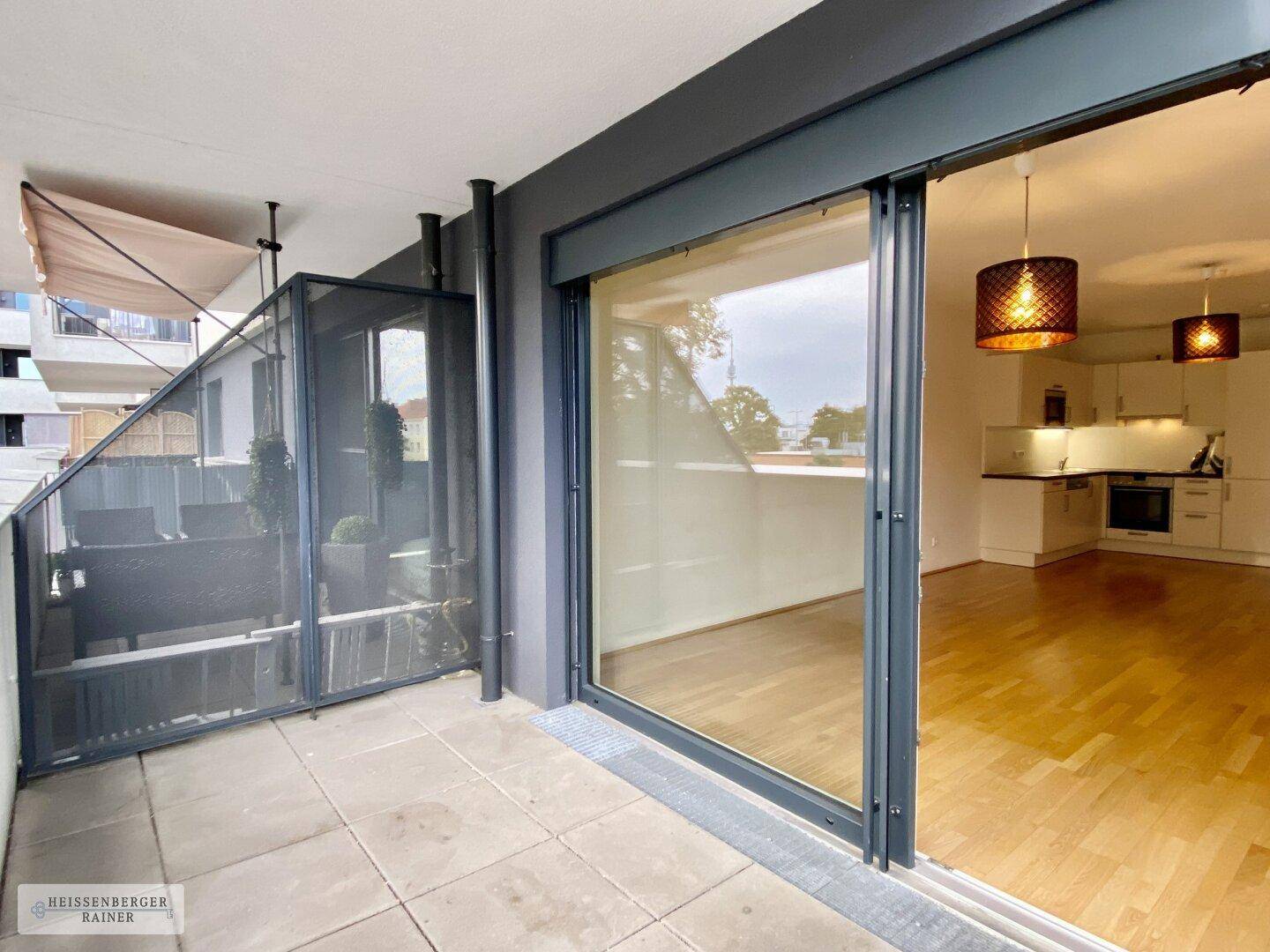 Geräumige Terrasse mit Fliesenboden und Sichtschutz, mit großen Schiebetüren zum Innenbereich.