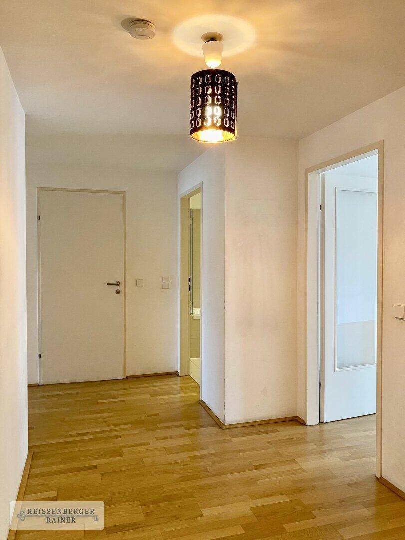 Heller Flur mit Holzboden und Zugang zu verschiedenen Räumen, ausgestattet mit moderner Deckenleuchte.