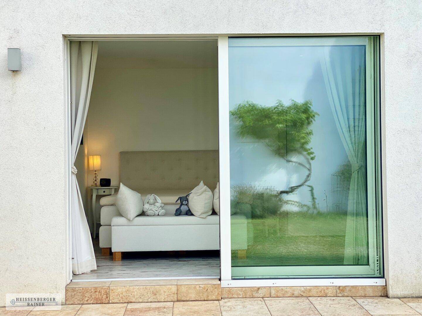 Schlafzimmer mit großzügiger Glasschiebetür, die direkten Zugang zum Garten und viel Tageslicht bietet.