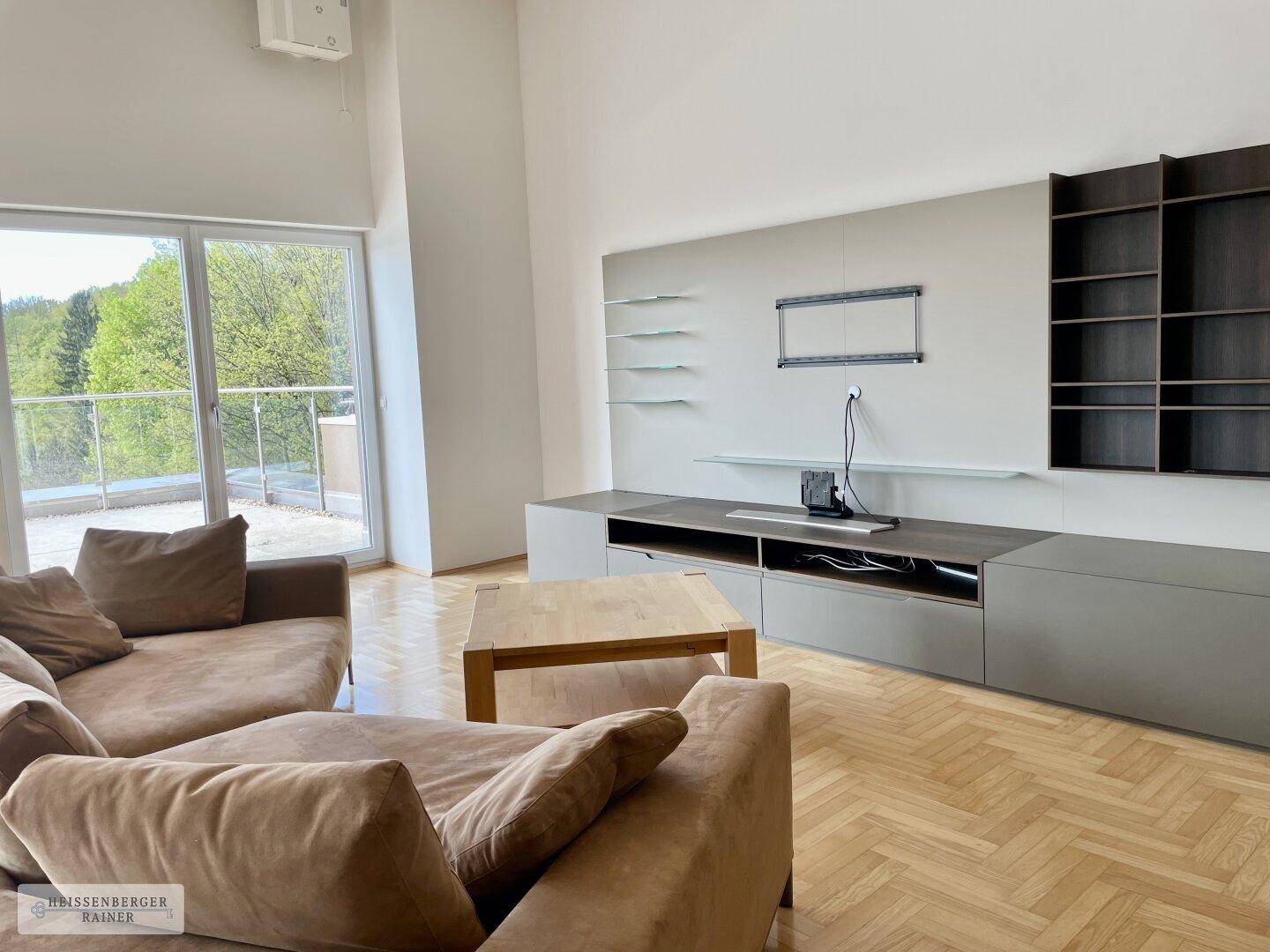 Virtuell inszenierter Wohnbereich mit beigem Sofa, Couchtisch und Blick auf die grüne Umgebung.