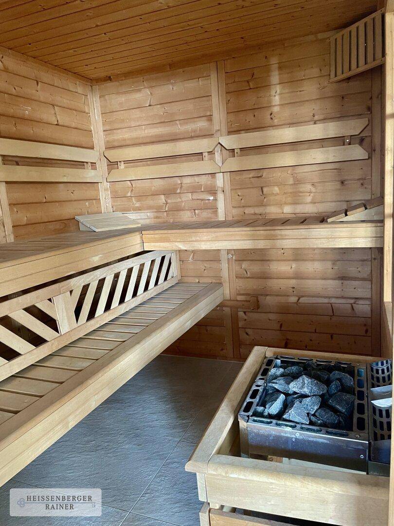 Gemütliche Holzsauna mit mehreren Bänken und traditionellem Saunaofen für Entspannung.