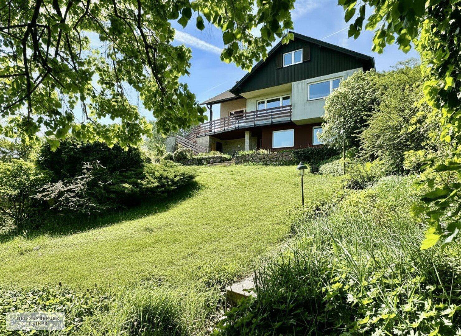 Charmantes Haus mit mehreren Balkonen, eingebettet in einen weitläufigen grünen Garten.