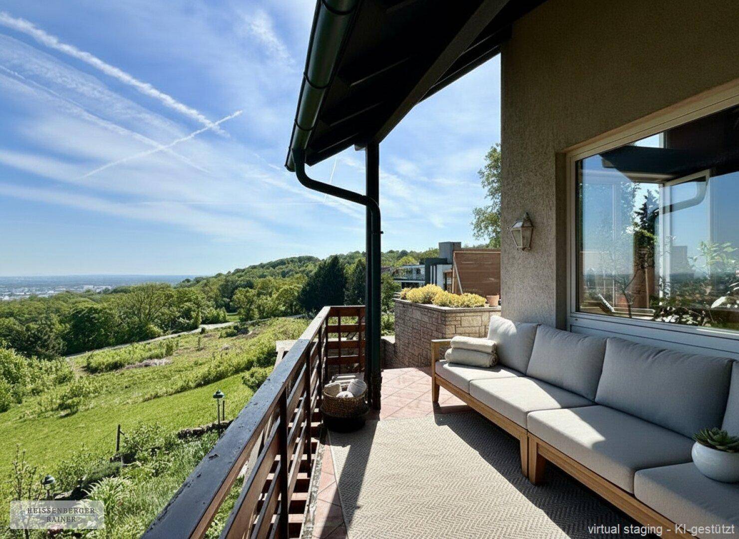 Geräumiger Balkon mit bequemen Gartenmöbeln und einem weiten Blick über die grüne Landschaft zur Stadt.