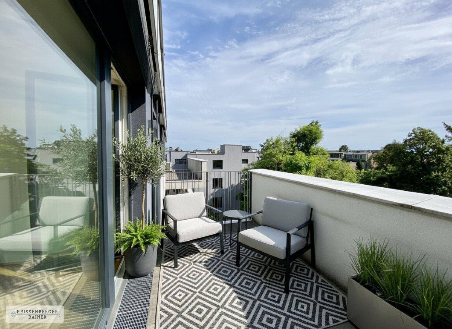 Kleiner Balkon mit Sitzgelegenheiten, Pflanzen und Blick auf die Stadt.
