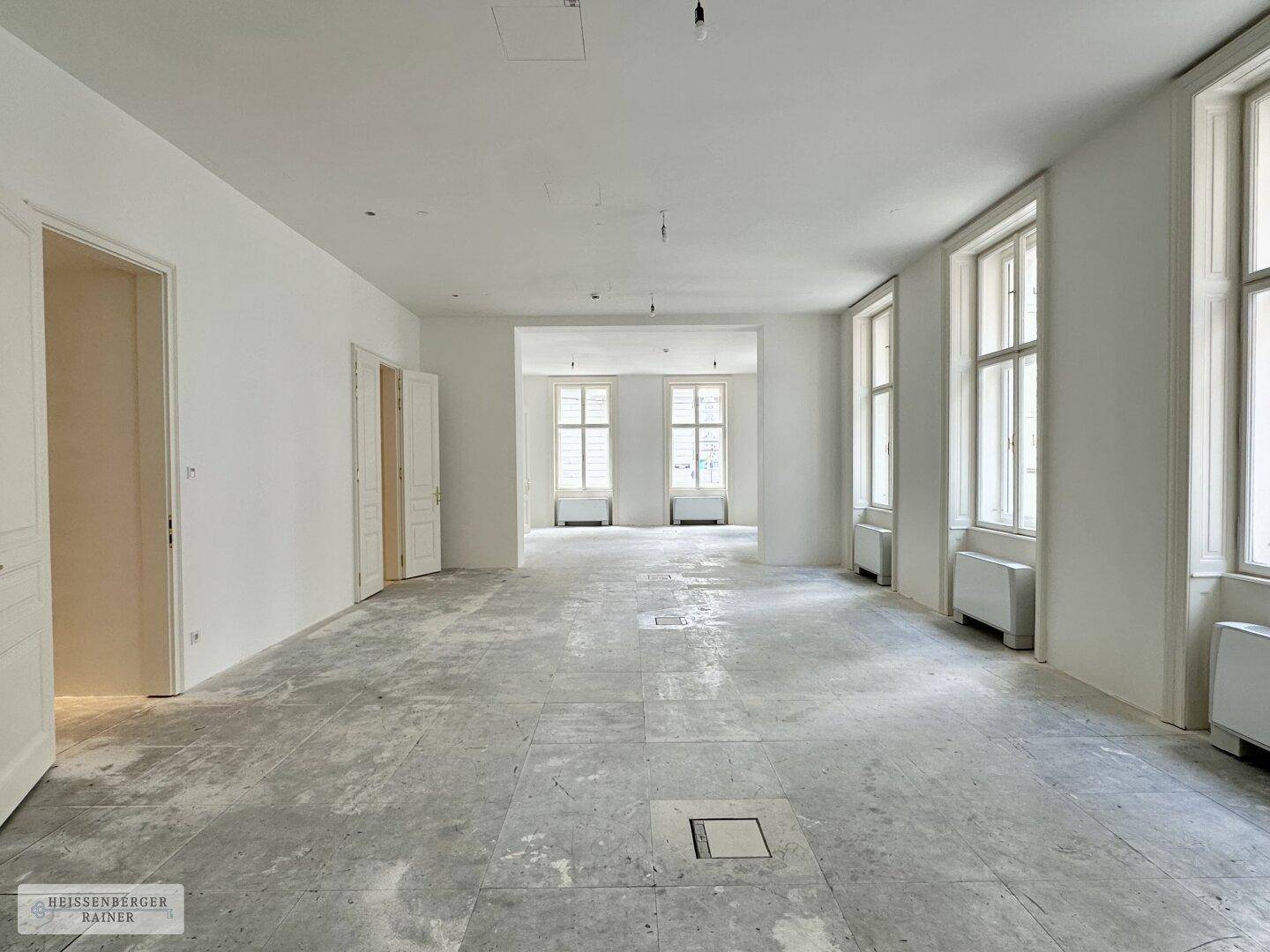 Geräumiger, heller Innenraum mit vielen Fenstern und vorbereitetem Bodenbelag für zukünftige Nutzung.
