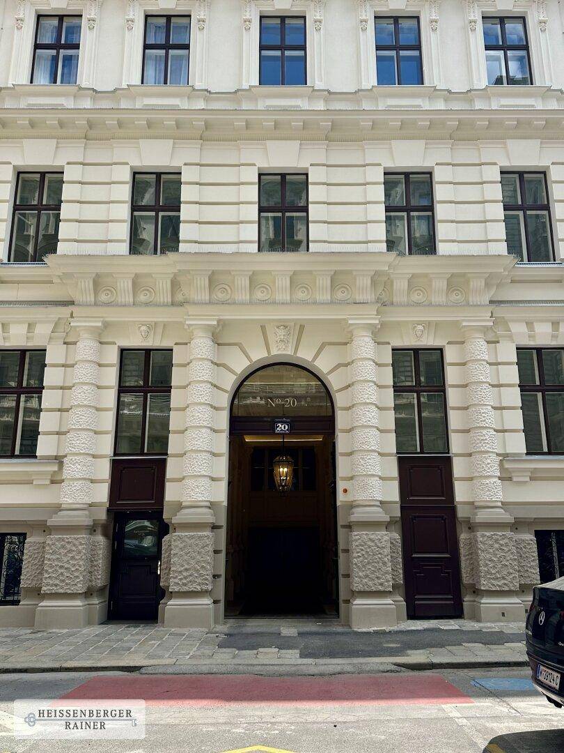 Klassische Fassade eines historischen Gebäudes mit symmetrischen Fenstern und einem verzierten Eingang.