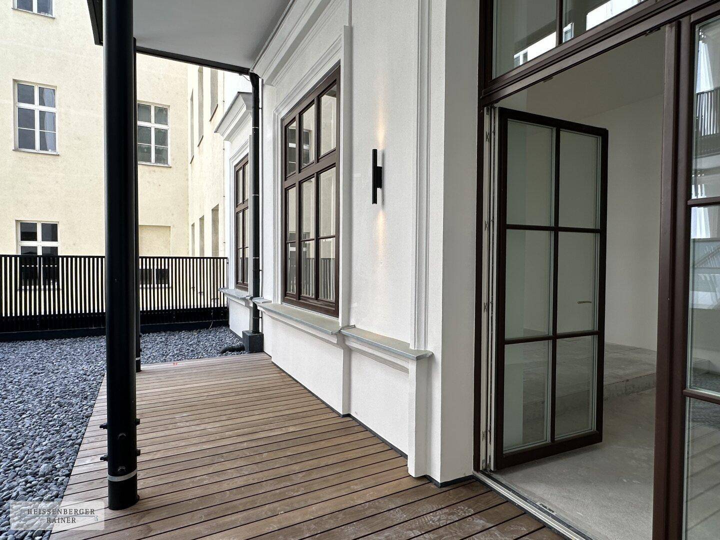Außenbereich mit Holzboden und Kiesbett, direkt an das Gebäude angrenzend, bietet Platz im Freien.