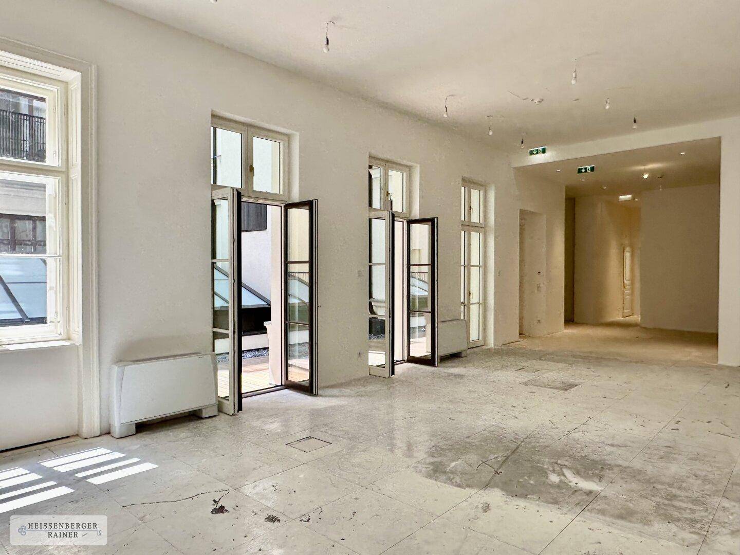 Heller, weitläufiger Bürobereich mit mehreren Fenstern und einem robusten Steinboden.