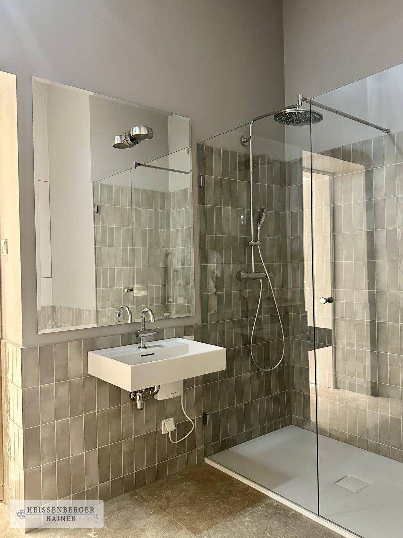 Elegantes Badezimmer mit großer begehbarer Dusche, Regendusche und modernem Waschtisch.